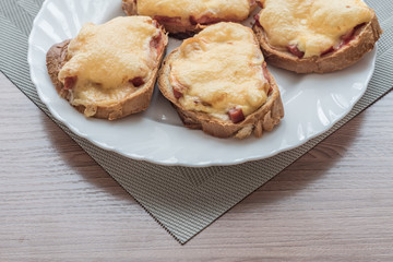 close-up of baked hot sandwiches with cheese and sausage on white plate