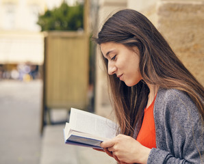 Obraz premium Young attractive student in red dress studying and reading a book.