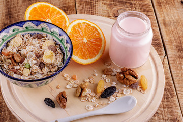 Healthy breakfast. Ceramic bowl with oat flakes, dried fruits, nuts on wood background