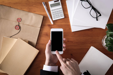 Smart phone and business items on wooden table
