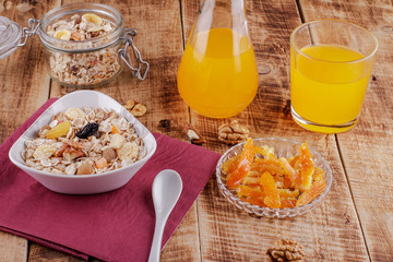 Healthy breakfast. Ceramic bowl with oat flakes, dried fruits, nuts on wood background