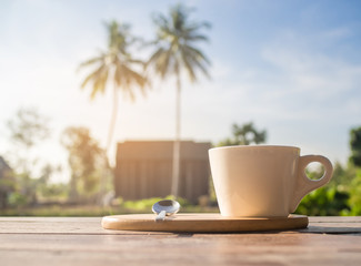 A cup of hot coffee on wooden table in the morning.