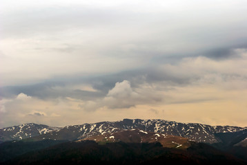 Wind matured clouds and snowy mountain peaks moody scene