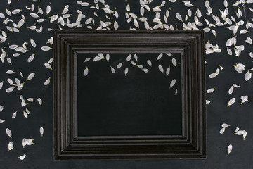 top view of vintage wooden frame with petals over black background