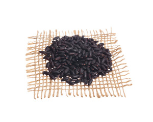 Black Rice. Grains over hessian fabric, isolated white background.