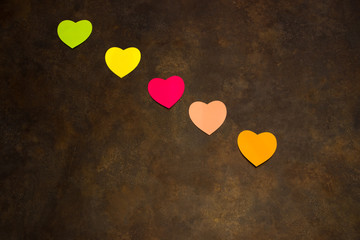 Hearts of various colors on brown background for St. Valentine's Day