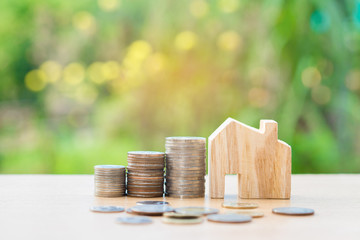 Coin money and house model on table and green background. Finance and banking concept.
