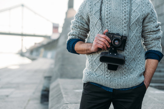cropped shot of man in stylish sweater with vintage film camera outdoors