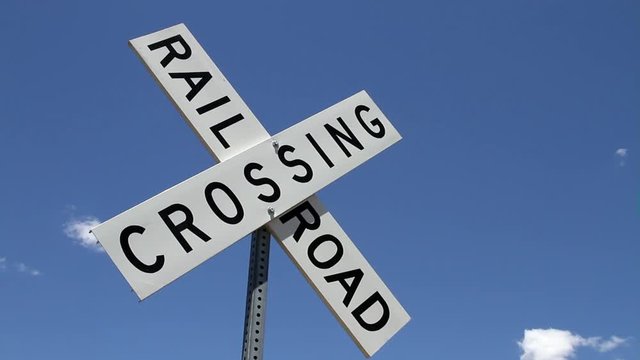 Railroad crossing sign under blue sky, USA
