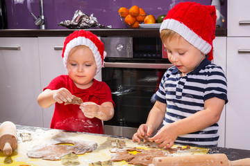 Cute little boy and girl twins preparing Christmas cookies in the kitchen