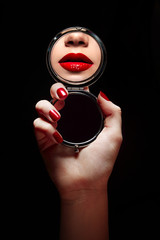 A beautiful young girl looks in the mirror and sees a reflection of red lips.Beauty, fashion,...