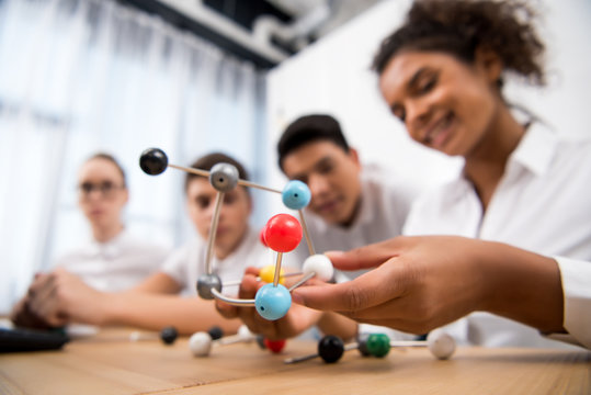young students picking molecular model for chemistry lesson