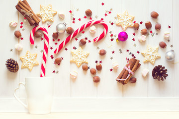 Christmas tea cup with gingerbread cookies and other sweets on white wooden background. Top view