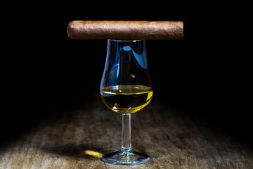 A glass of whiskey with a cigar