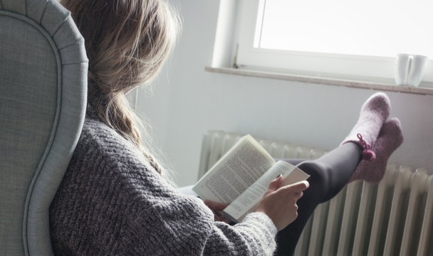 Junge Frau entspannt im Sessel und liest ein Buch