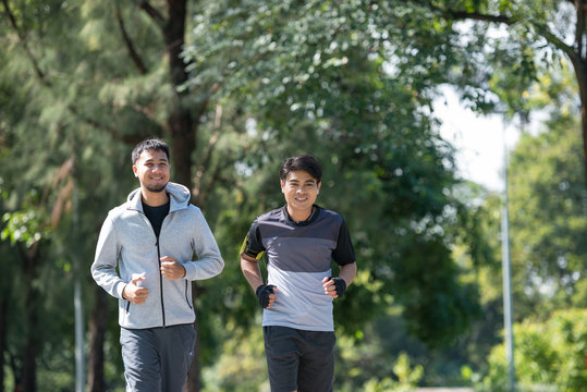 Two Young Fitness Man Running At Morning In The Garden, Park