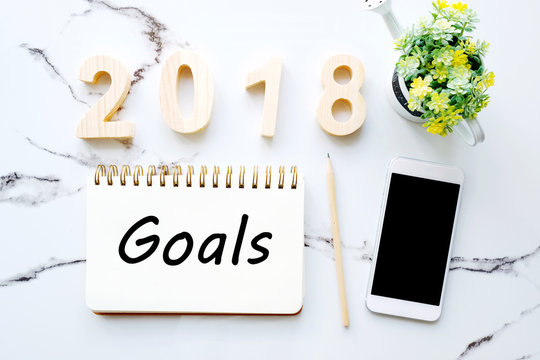 2018 goals on notebook paper and smart phone at office desk background, banner, sign business new year, aim to success in business
