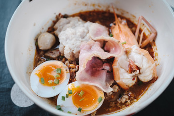 top view spicy tom yum fusion noodle, with bacon, egg, prawn and pork
