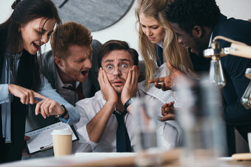 businessman having trouble with deadline while colleagues shouting at him