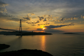 Amazing zooming out aerial view of the Russky Bridge, the world's longest cable-stayed bridge, and the Russky (Russian) Island in Peter the Great Gulf in the Sea of Japan. Sunrise. Vladivostok, Russia