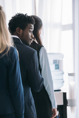 young handsome african american manager standing in queue for water dispenser at office