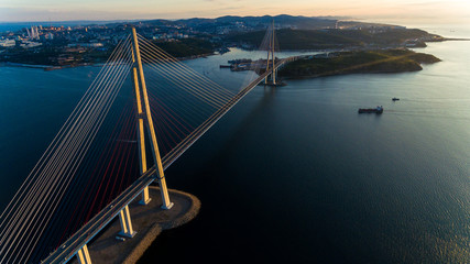 Amazing zooming out aerial view of the Russky Bridge, the world's longest cable-stayed bridge, and the Russky (Russian) Island in Peter the Great Gulf in the Sea of Japan. Sunrise. Vladivostok, Russia