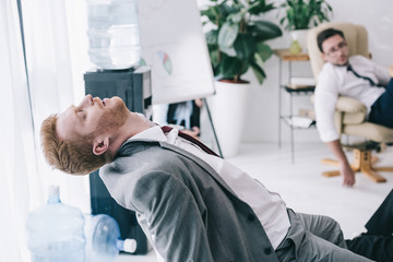 exhausted businessman sleeping on chair at messy office