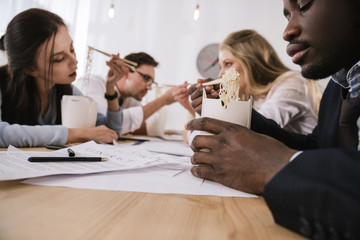 close-up shot of businesspeople eating noodles together at office