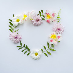 Frame of chamomiles, branches, leaves and lilac petals on white background. Flat lay, top view