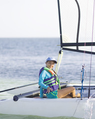 Naklejka premium Beautiful teenager sailing catamaran in beautiful sunset.