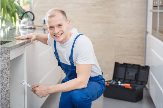 Smiling professional plumber with tools