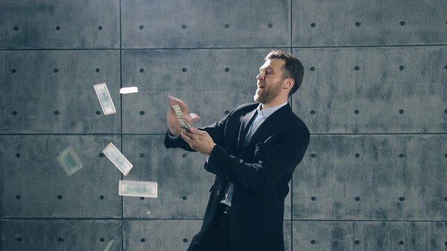 Man in formal suit dancing and throwing money. Slow motion