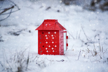 Red lantern with burning candle on fresh snow. Snowy winter morning in park.