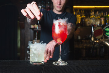 The barman mixes alcohol in a cocktail. Create a beautiful alcoholic cocktail at the bar.