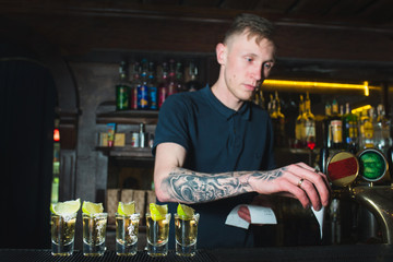 Beautiful alcoholic shots against the background of a bartender at work. The work of the bartender.
