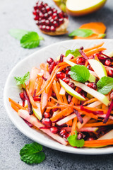 Colorful carrot beetroot apple pomegranate salad on stone background. Selective focus, copy space.