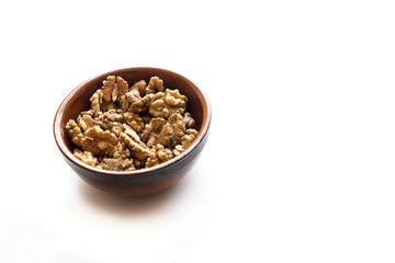 a lot of natural walnuts in a brown ceramic bowl isolated on the white background