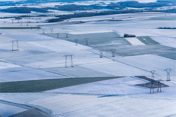 Fototapeta na wymiar Vue aérienne de poteaux électriques et de champs sous la neige