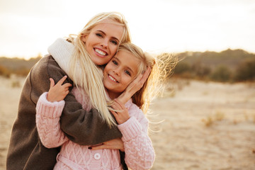 Smiling mother playing with her little daughter - obrazy, fototapety, plakaty