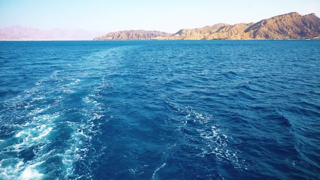  Ship moves on the high seas against the backdrop of mountains. Red Sea on the background of coast and beaches.