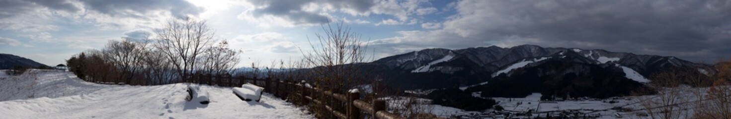 雪に埋もれたベンチと山々のパノラマ