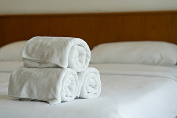 Fototapeta na wymiar White towels roll up on bed in hotel bedroom