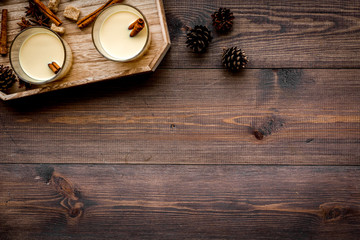 Winter attributes. Glasses of classic eggnog with spices on dark wooden background top view copyspace