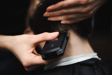 Master cuts hair and beard of men in the barbershop, hairdresser makes hairstyle for a young man