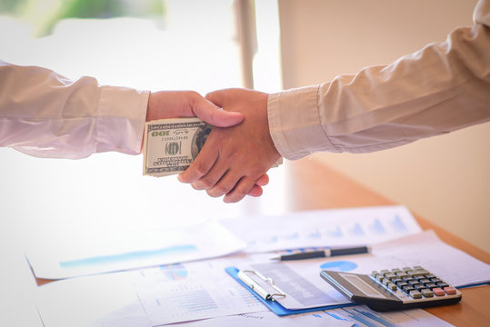 Cropped Image Of Businessman Bribing Partner While Shaking Hand Outdoors