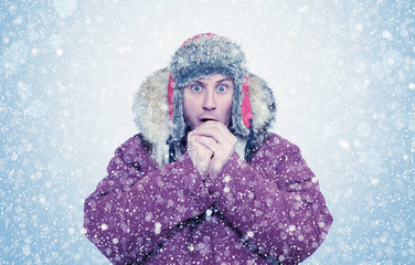 Frozen man in winter clothes warming hands, cold, snow, blizzard - obrazy, fototapety, plakaty