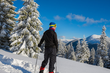 Adventurer in a goggles stands in mountains among deep snow