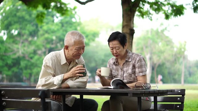 Asian senior retire couple drink coffee and read book in park
