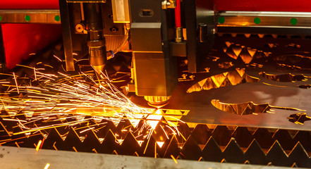 Laser cutting machine cutting the sheet metal with the sparking light. modern industrial...