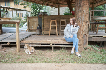 Beautiful asia woman sitting on wood with dog.